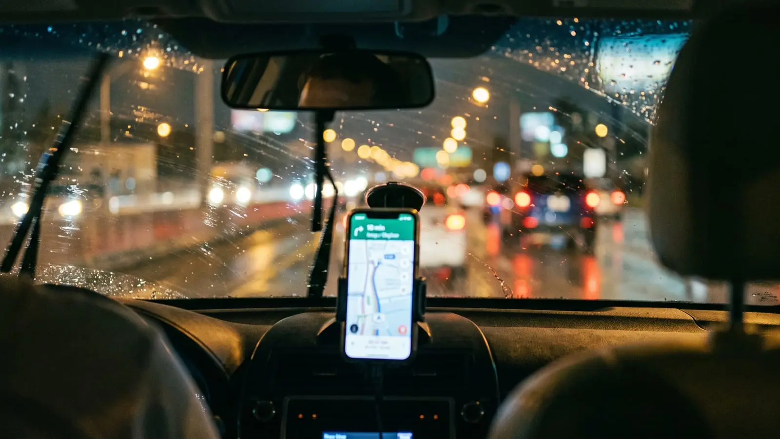 Vista desde el asiento trasero de un auto de Uber o Lyft de noche en Miami, con el GPS en el tablero